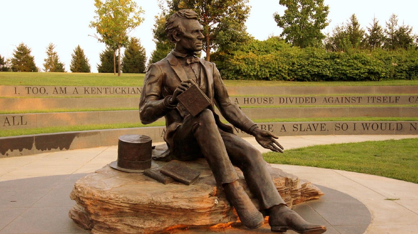 A bronze statue of Abraham Lincoln sits in a circular plaza surrounded by an engraved wall