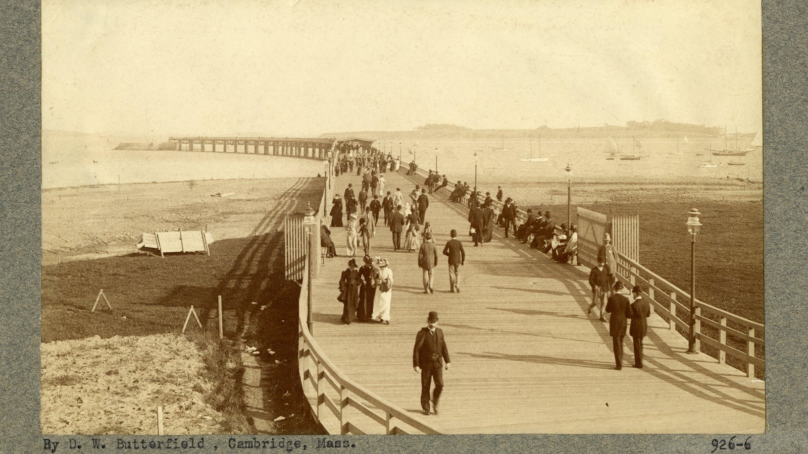 Black and white of wooden dock filled with people going out into the water