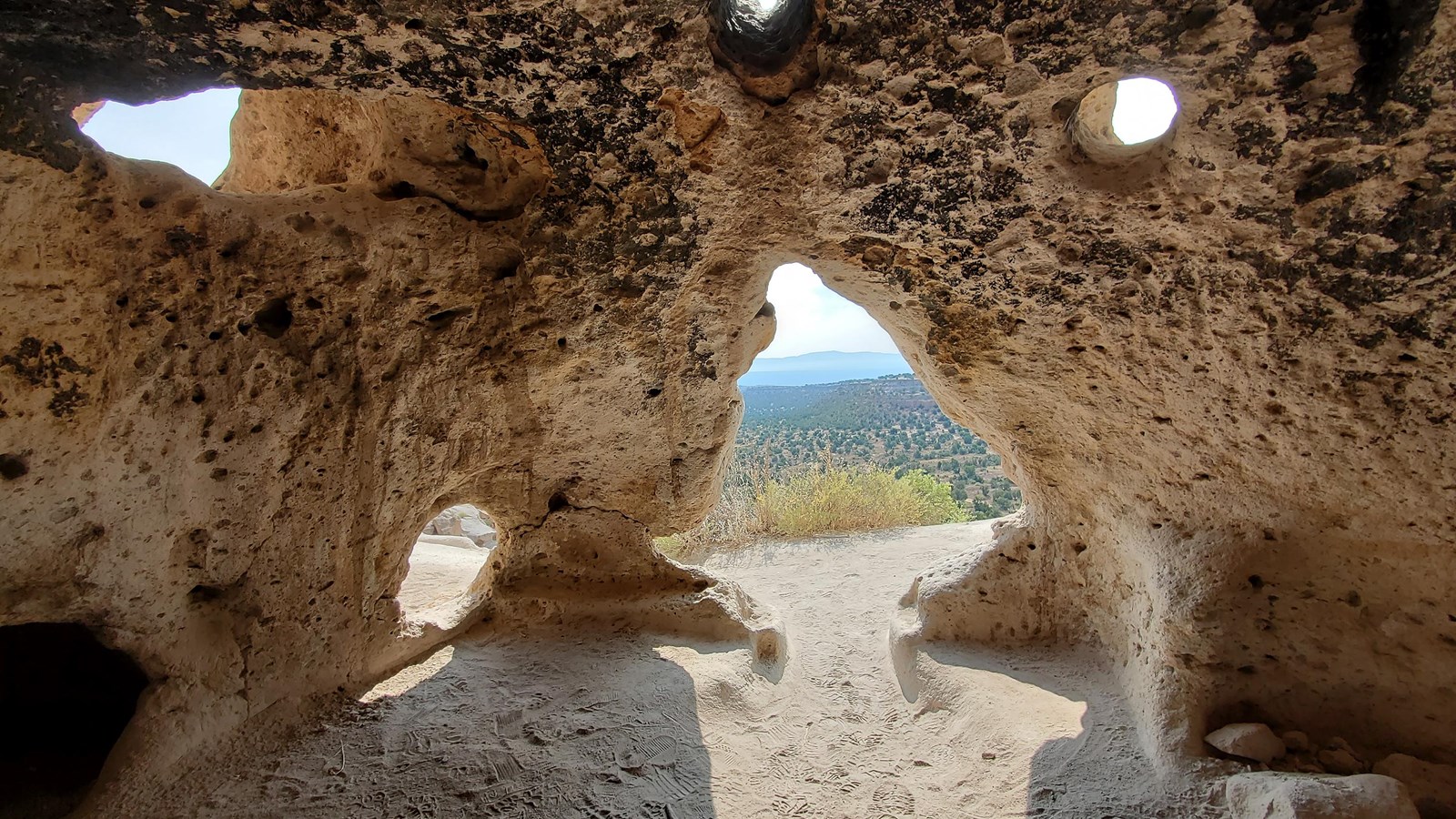 multiple openings in a tan rock wall let light into an opening