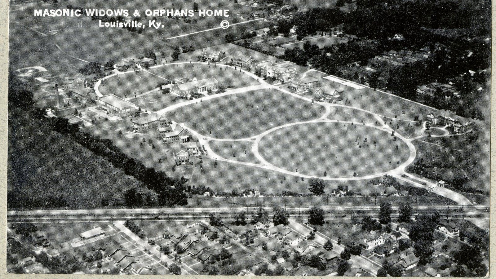 Black and white aerial of campus with curving paths, buildings on paths, open space in middle