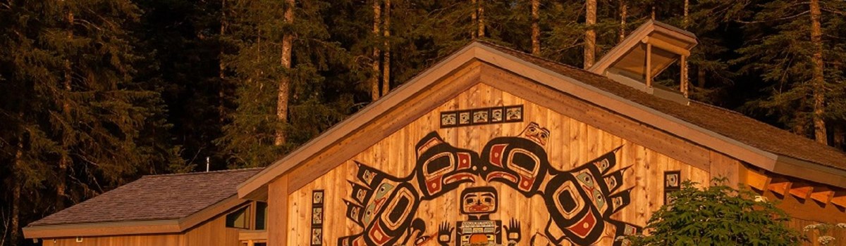 a large building with traditional alaska native carvings on the front at sunset