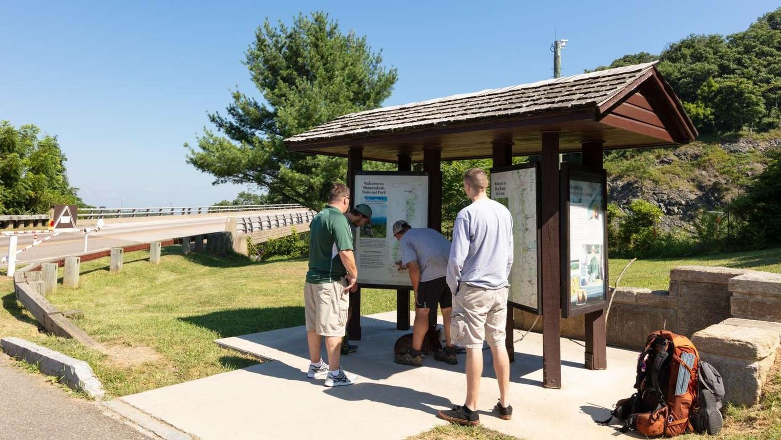 A color photograph of people looking at a shelter with two sets of informational panels.
