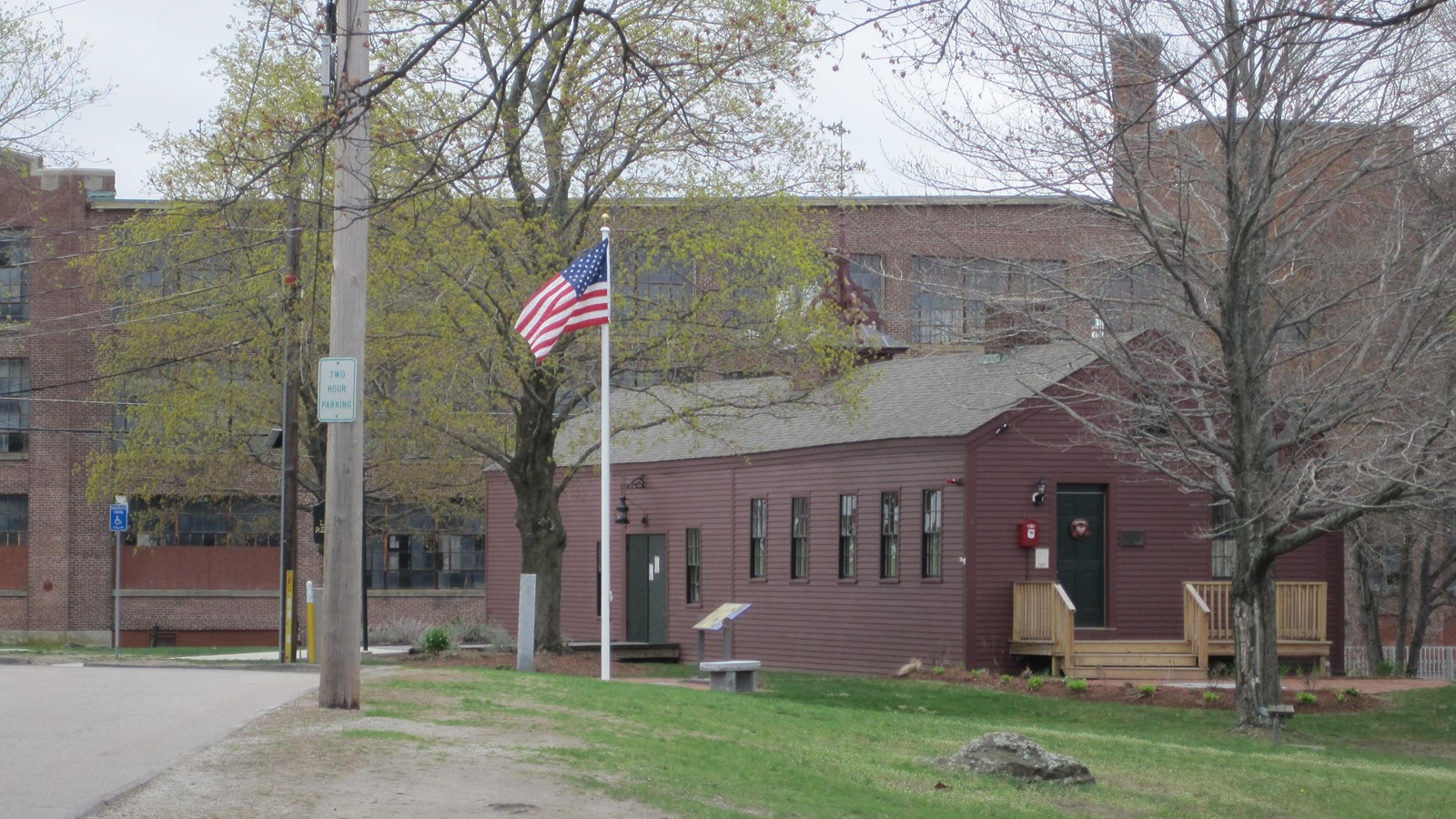 Little Red Shop stands in the foreground with large brick mill complex in background