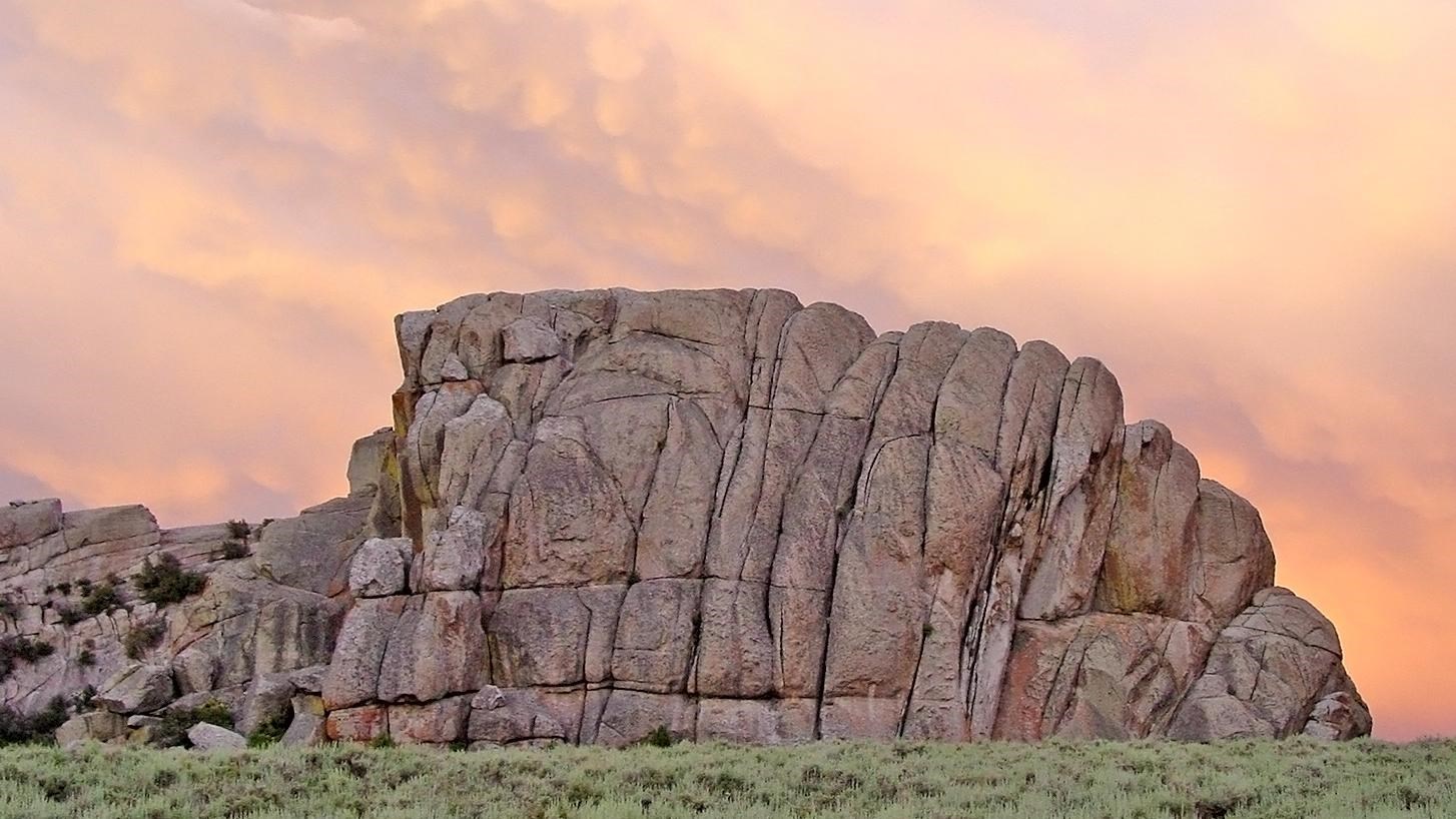 Rock formation resembling a loaf of sliced bread with a vibrant pink sunset sky in the backdrop.