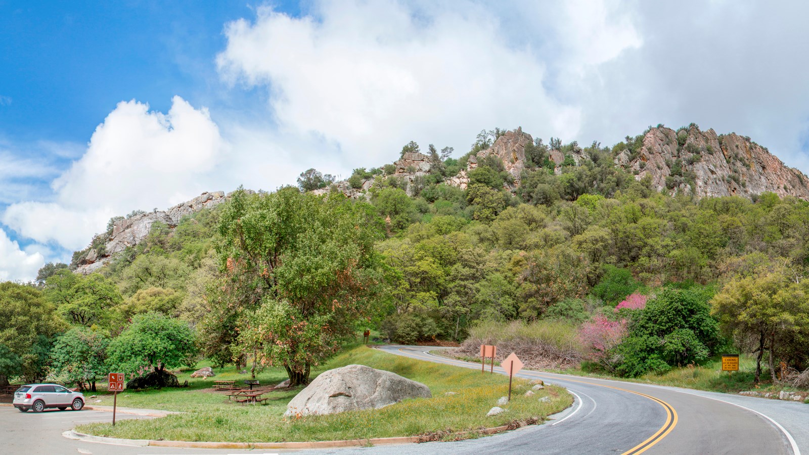 A paved road curves through the foothills vegetation past a picnic area.