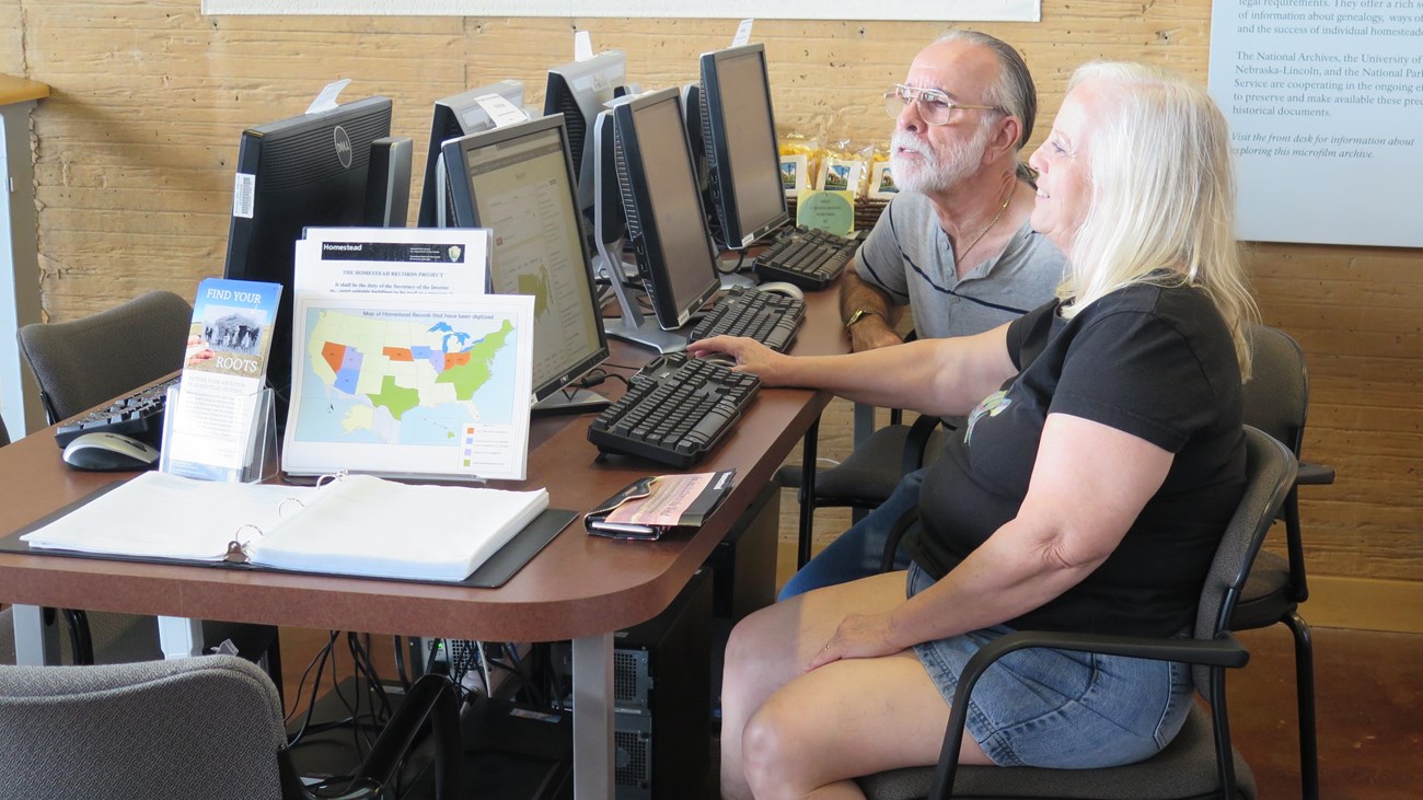 Two people sitting down and looking at records on computers