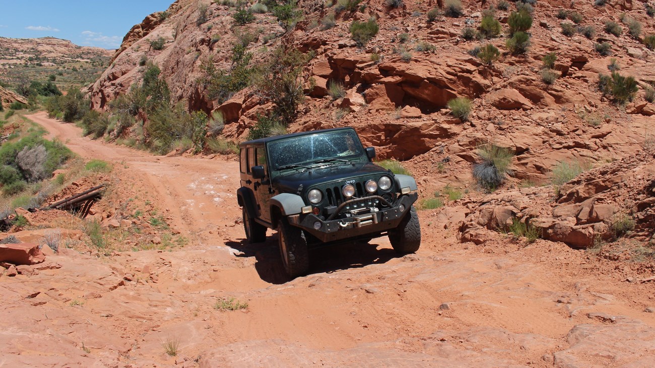 A jeep on a dirt road in a sandstone canyon