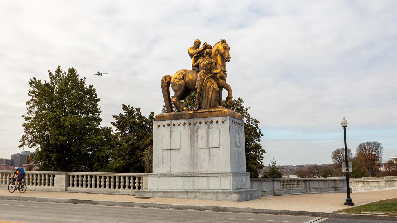 A golden statue of a horse beside a road. 