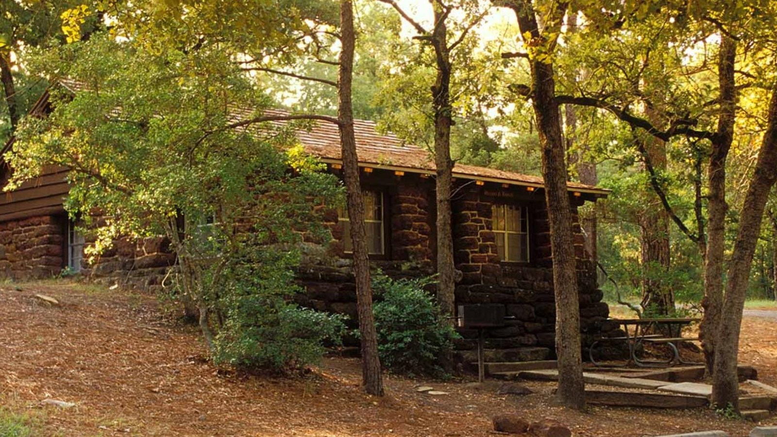 A one-story, brick building in a wooded forest.