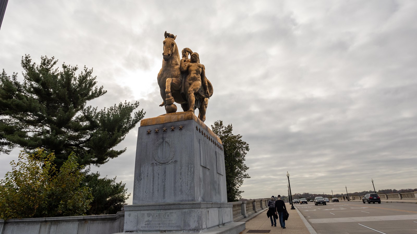 A golden statue of a horse next to a bridge.