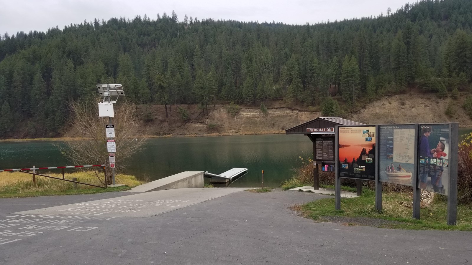 A paved boat launch is flanked by an information kiosk and other signs