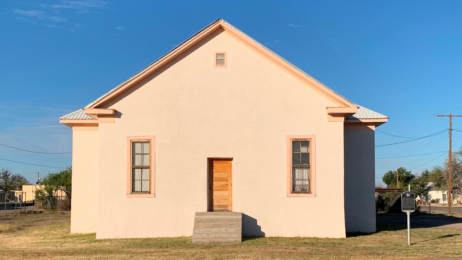 plain house with two small windows on either side of the centered door. Steps lead up to the door