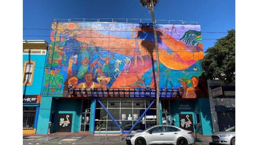 three-story building with glass windows and a colorful mural on the 2nd and 3rd floors