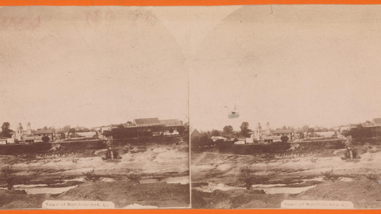 A sepia stereographic photograph of buildings in a town