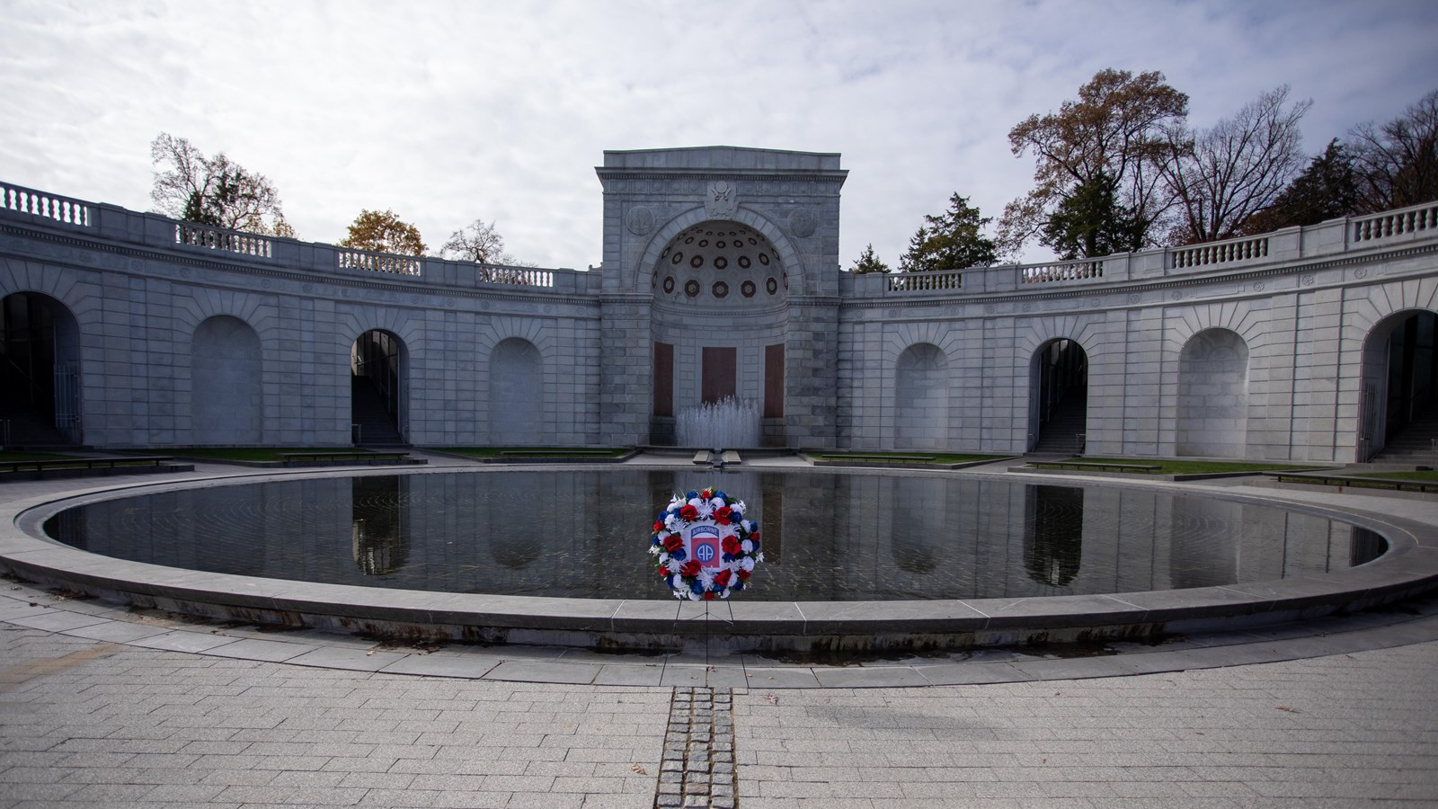 A large pool surrounded by a white stone structure with a short tower in the middle.