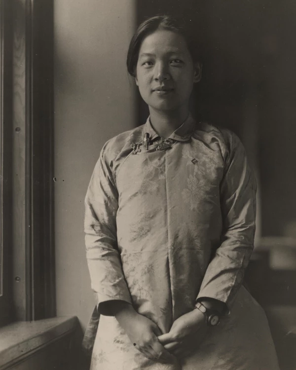 Half-length portrait of Miss Ting, standing by window, facing camera, hands clasped before her