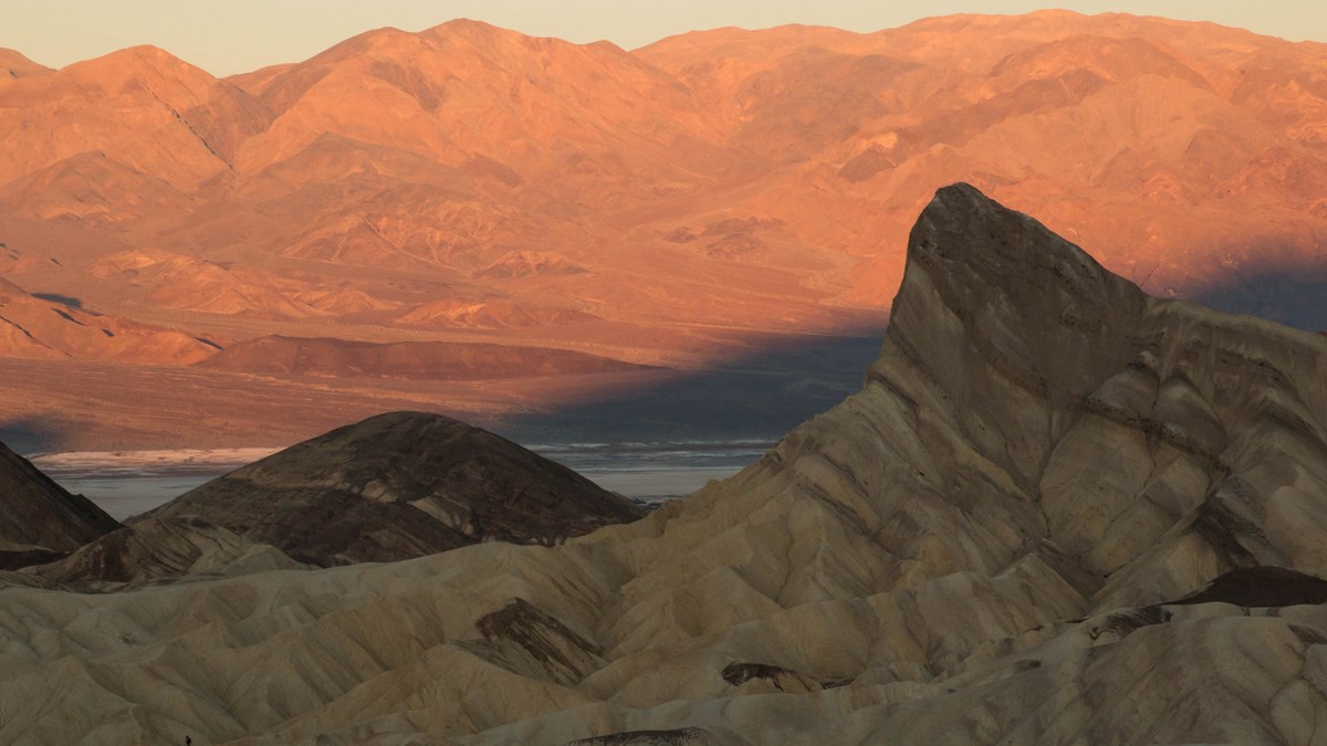badlands with orange and pink mountains behind