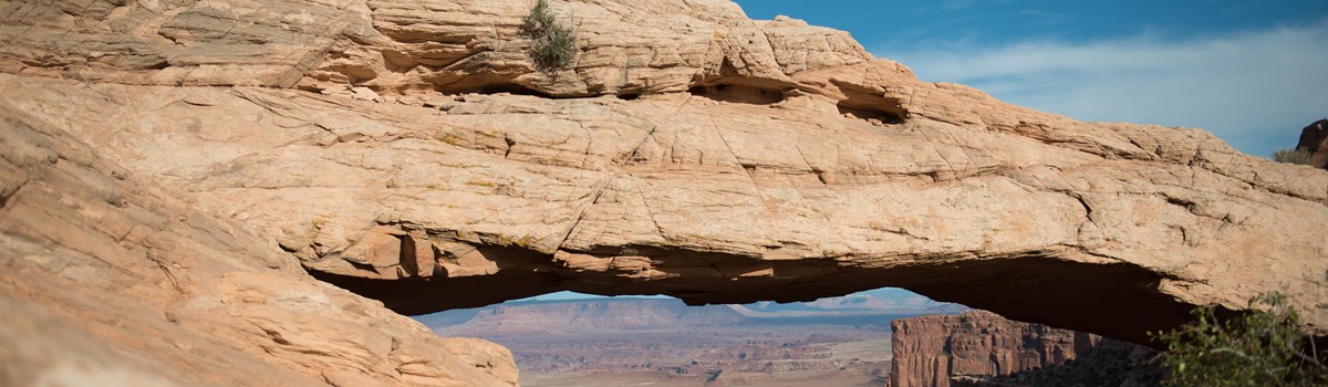 a broad, stone arch with canyons in the distance