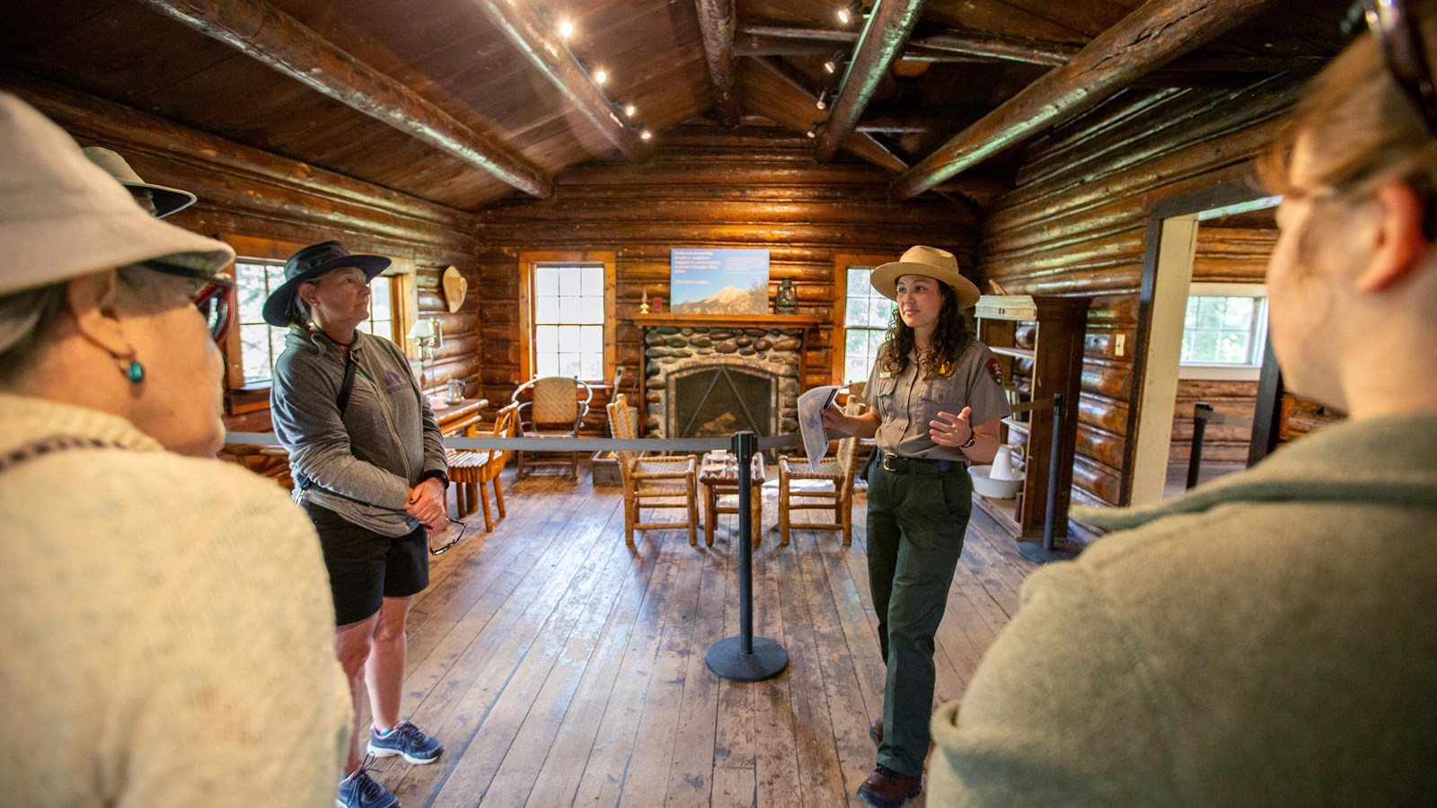 A ranger talking to visitors inside a historic log cabin.