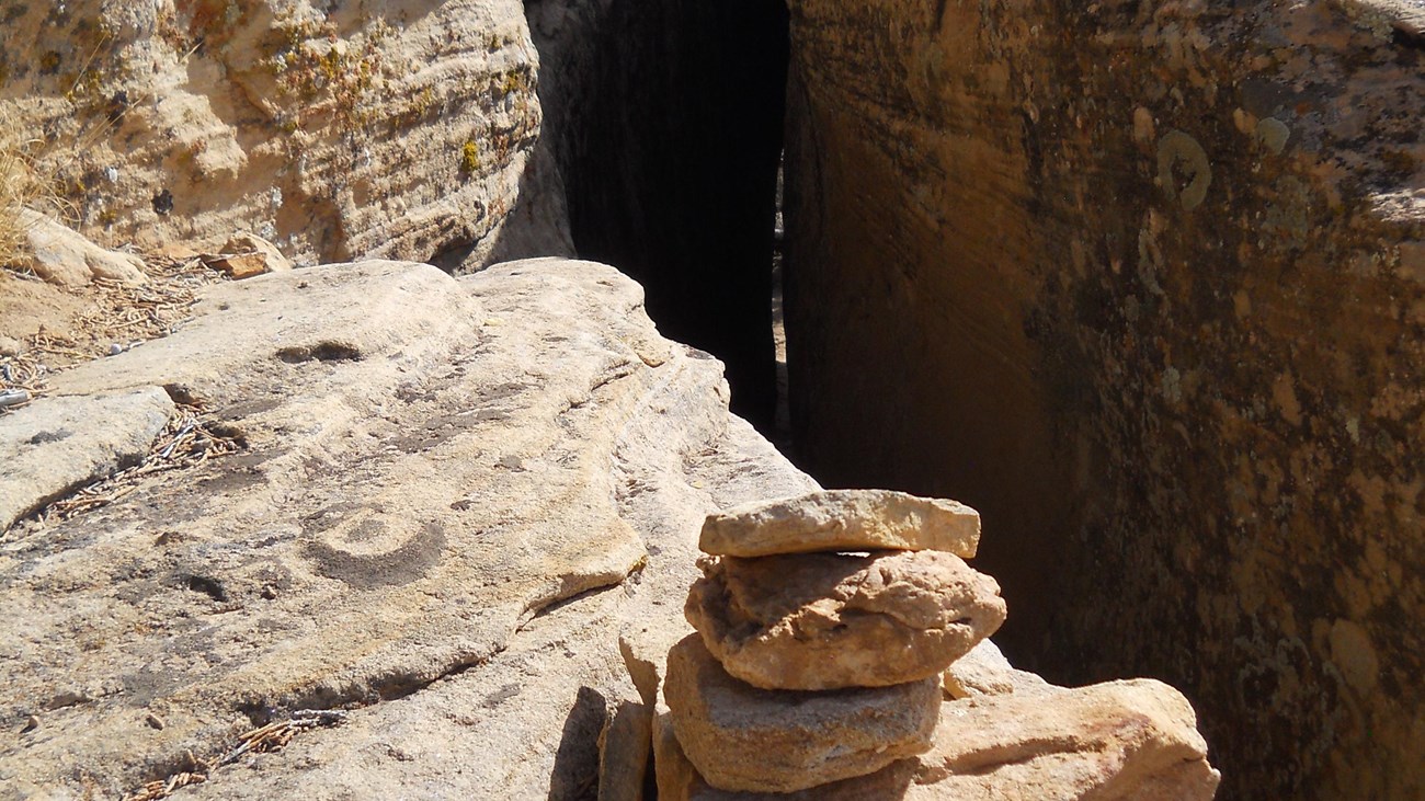 A stack of rocks by the entrance of a thin pathway through the rock 