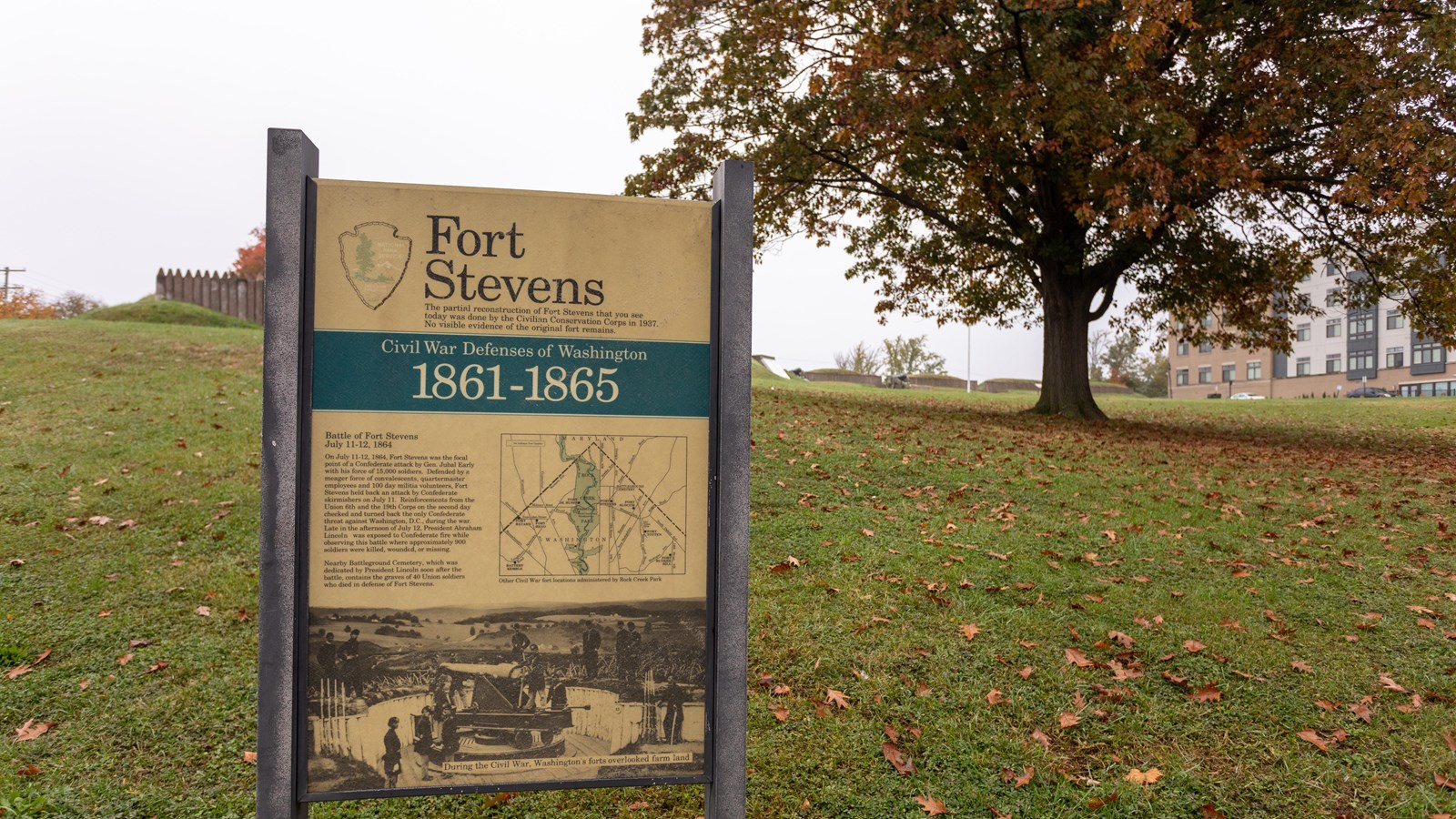 An informational panel in front of a large grassy field.