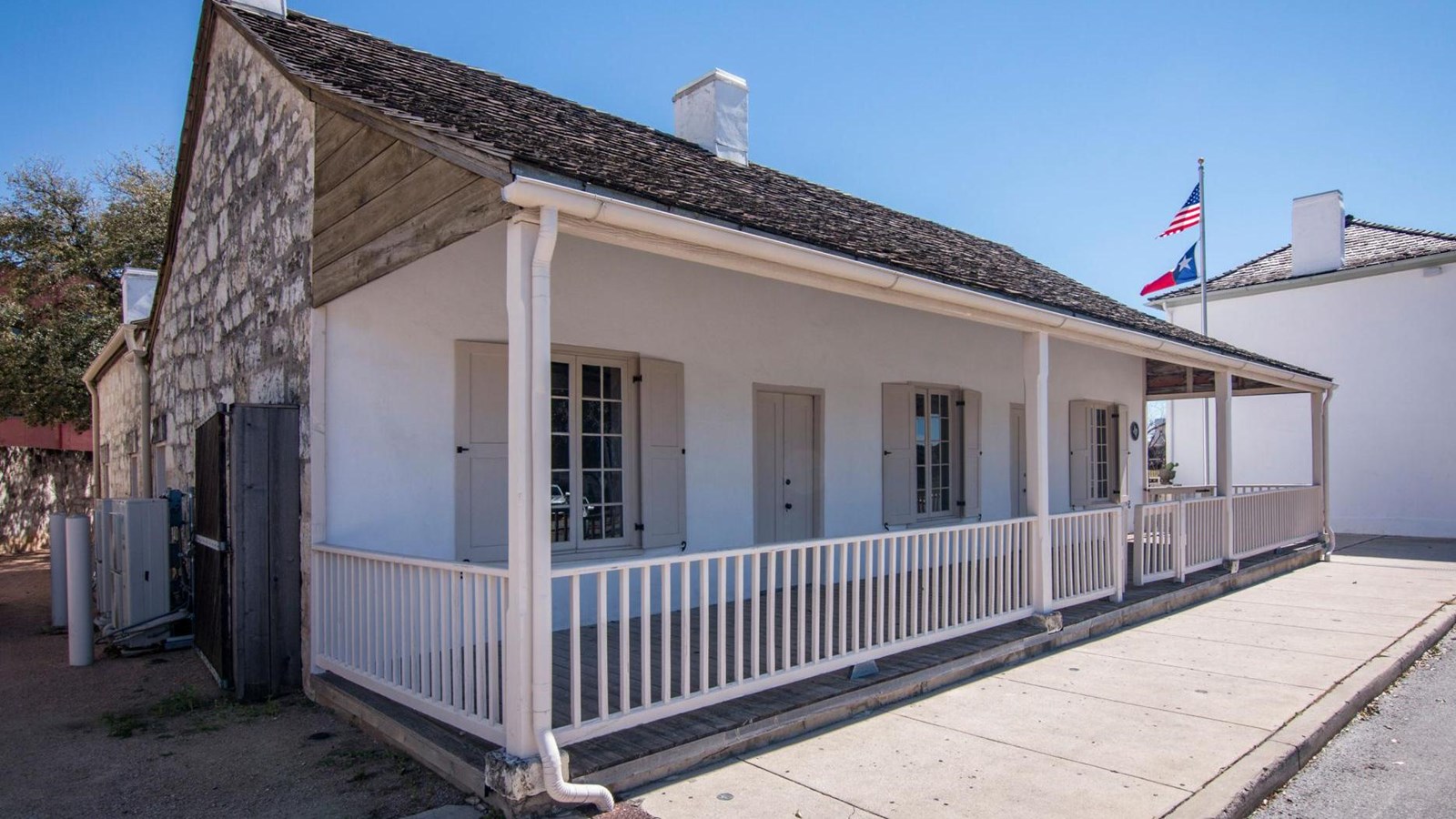 The exterior of a white house with a fenced porch.