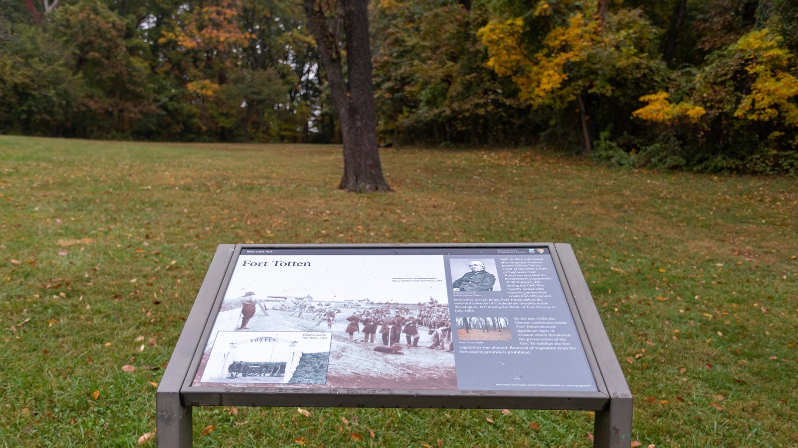 An informational panel in front of a grassy field. 