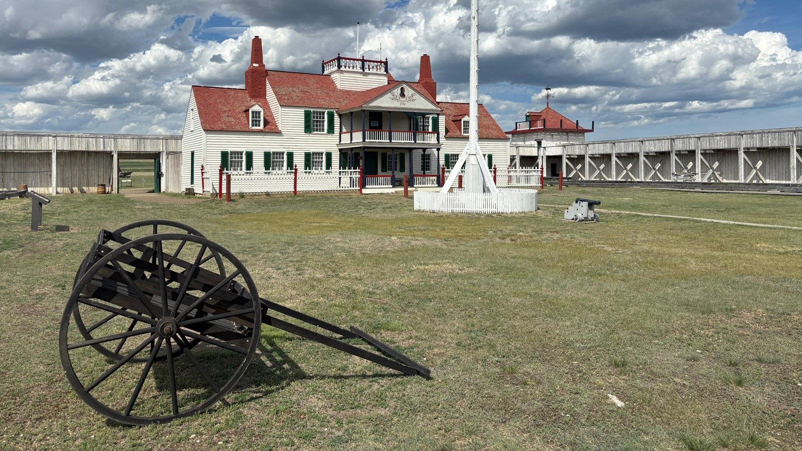 red-roofed building surrounded by tall fencing, with a smaller building on the corner of the fence.