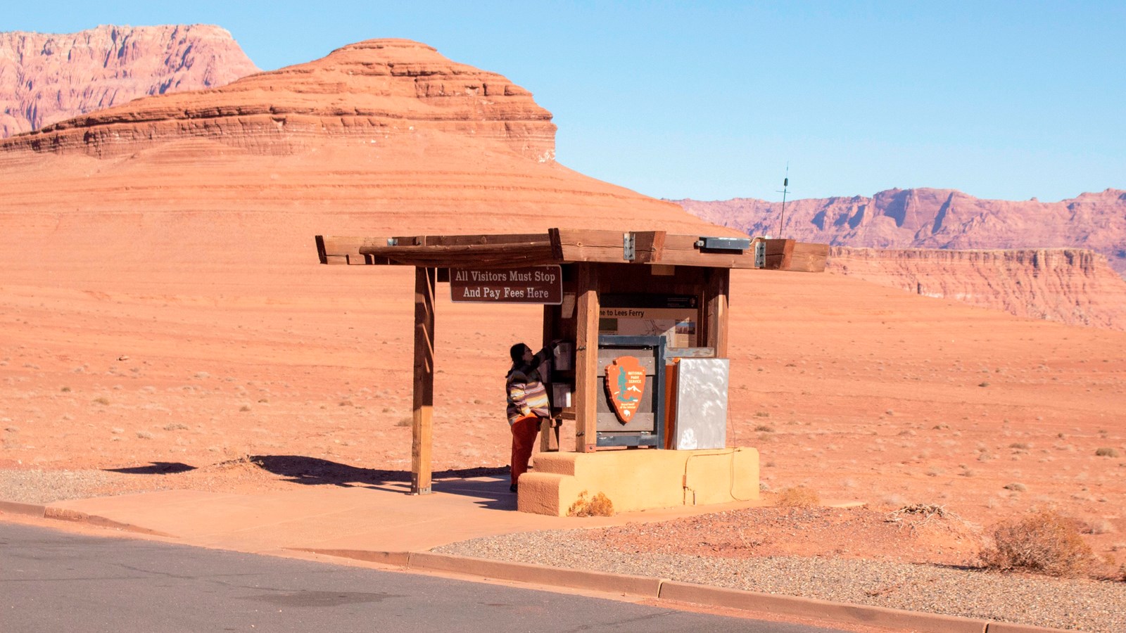 Wooden awning with signs attached to base. Person standing under awning looking at what