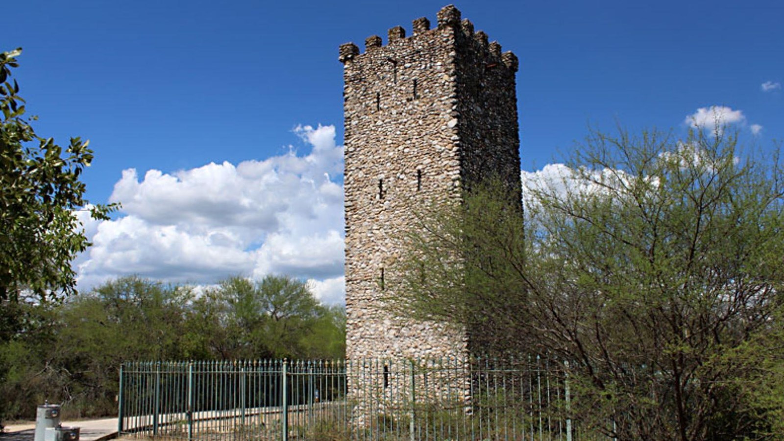 A large, four story column stone tower overlooking an expansive forest.