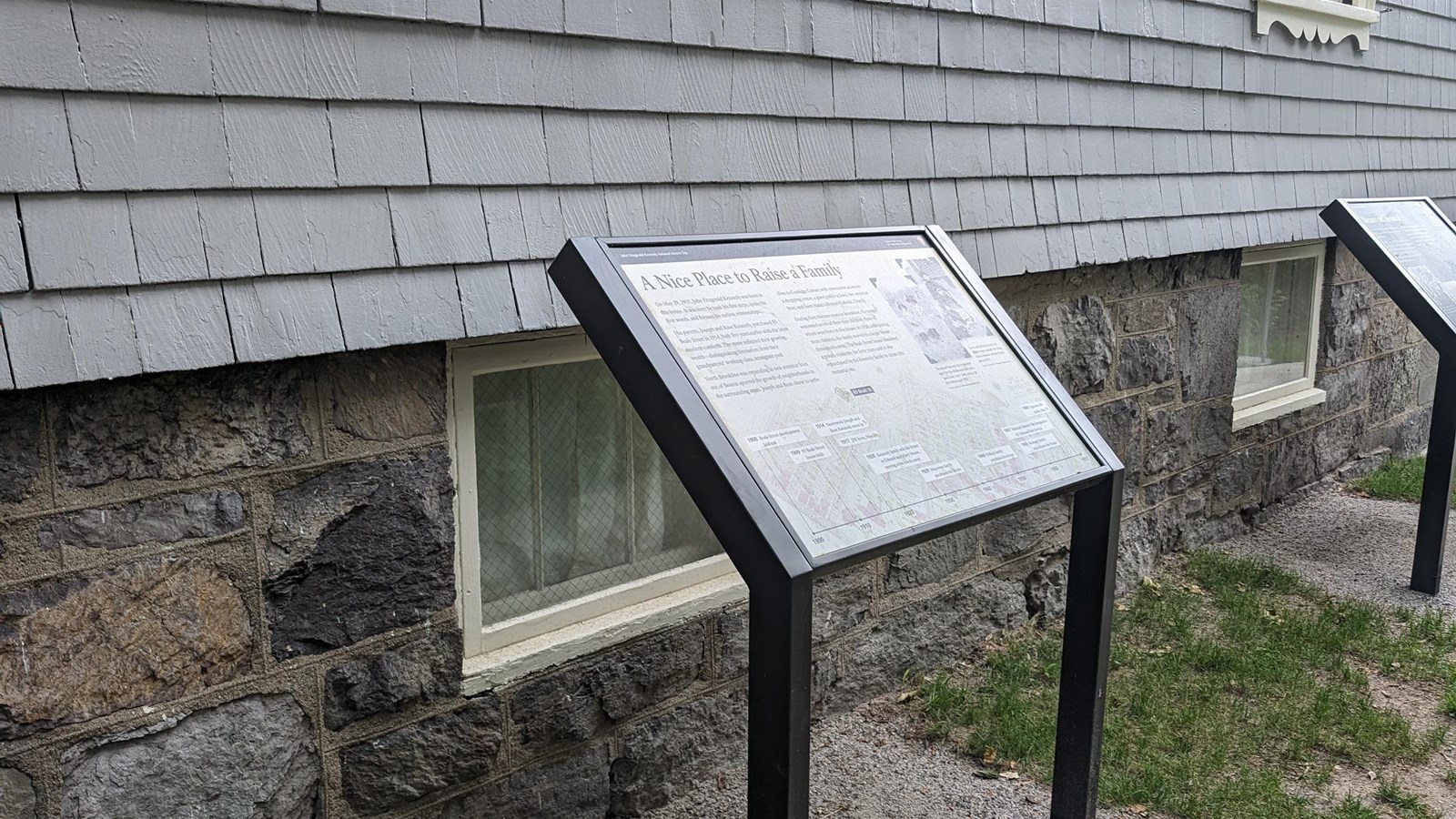 Wayside exhibit panel with map background next to gray building
