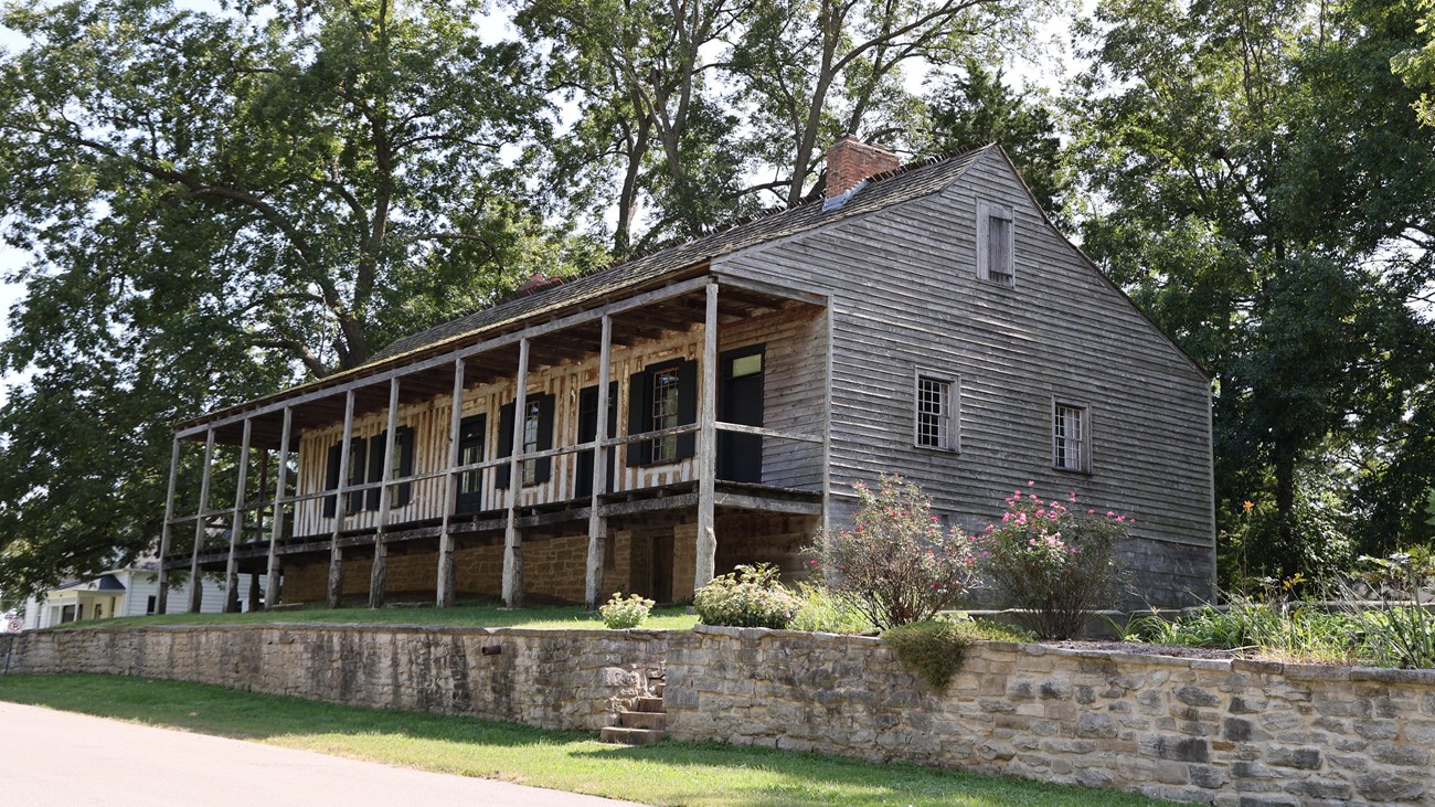 A large vertical log home with a wraparound porch.