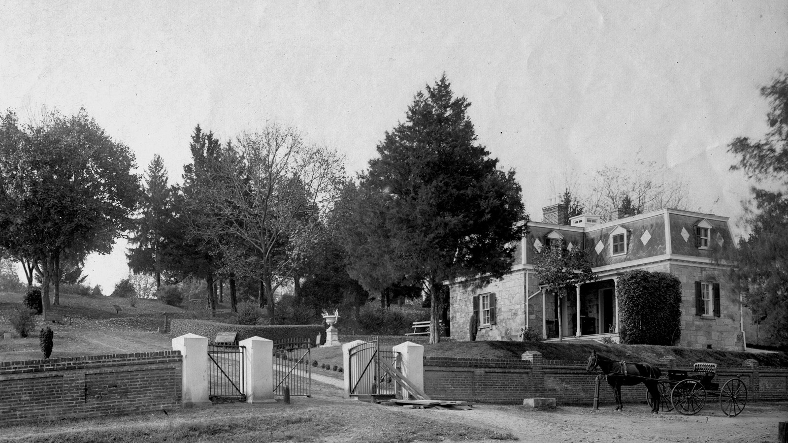 Historical black and white photo of cemetery lodge at gated entrance of cemetery.