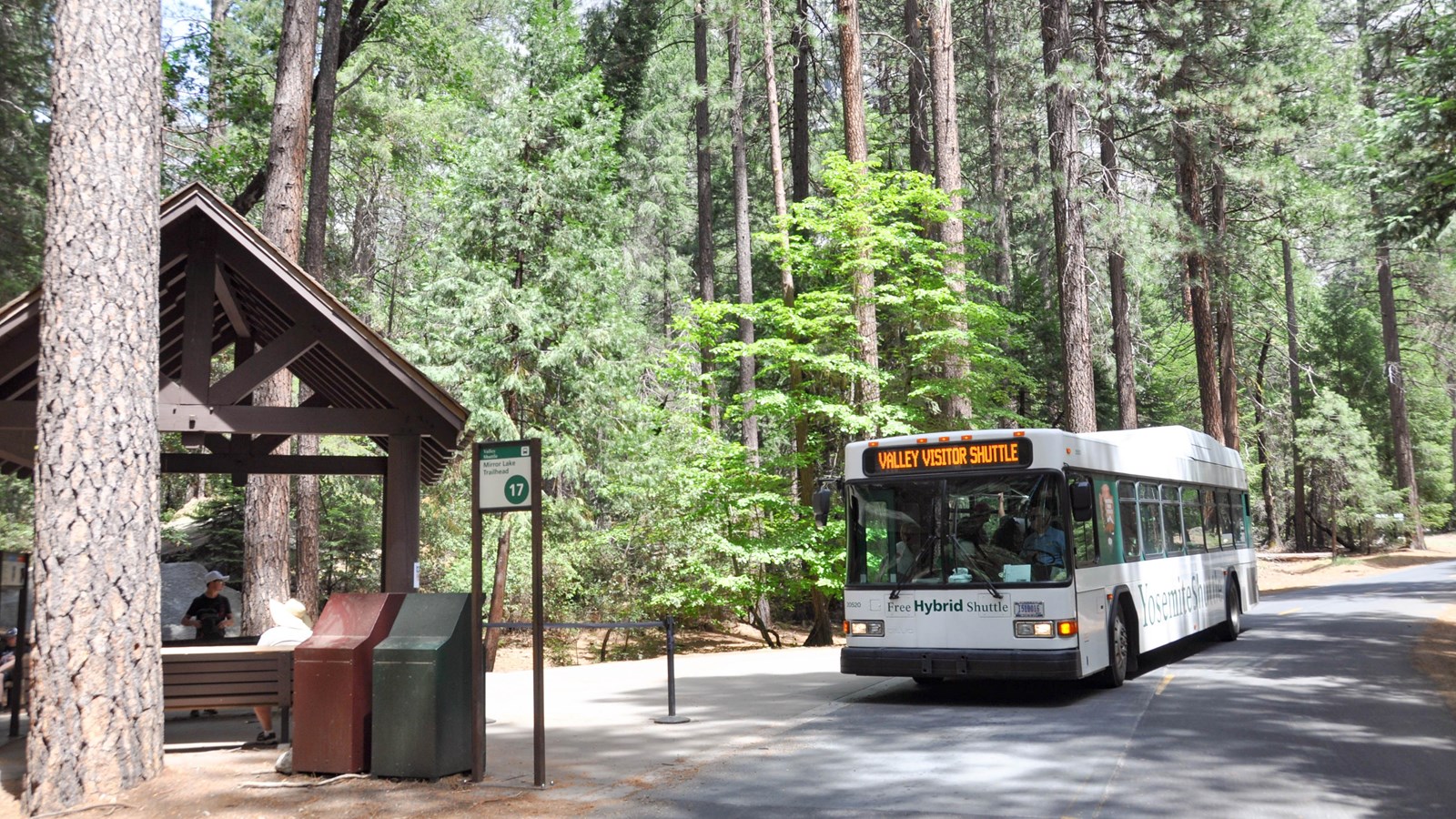 Bus pulling up to covered bus shelter along road