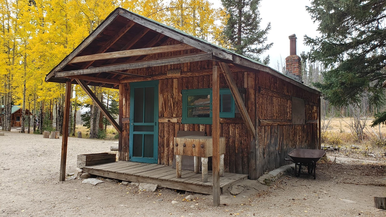 Wooden one-story log cabin with green trim.