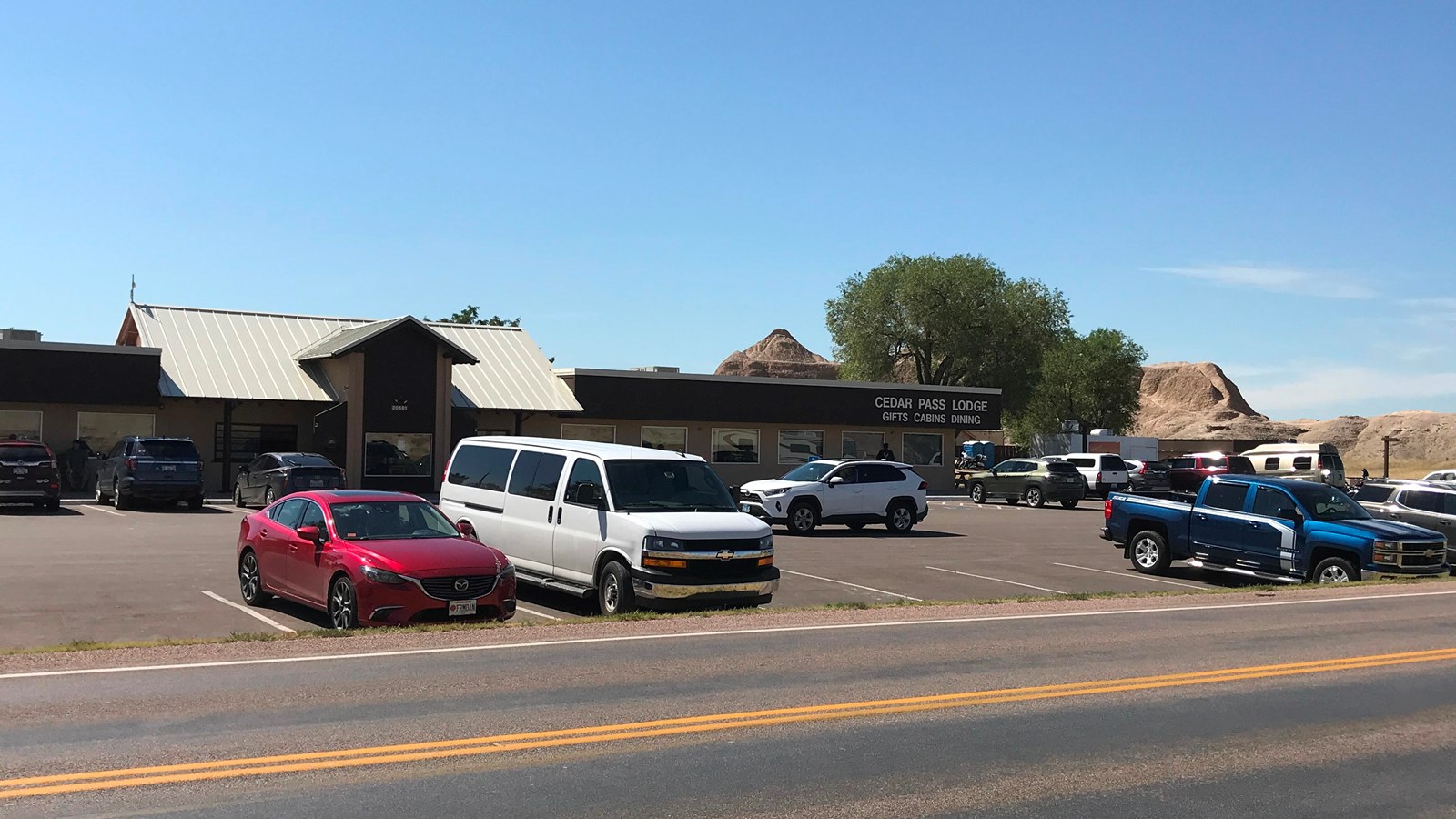 Multiple vehicles in a parking lot in front of a tan building labeled 