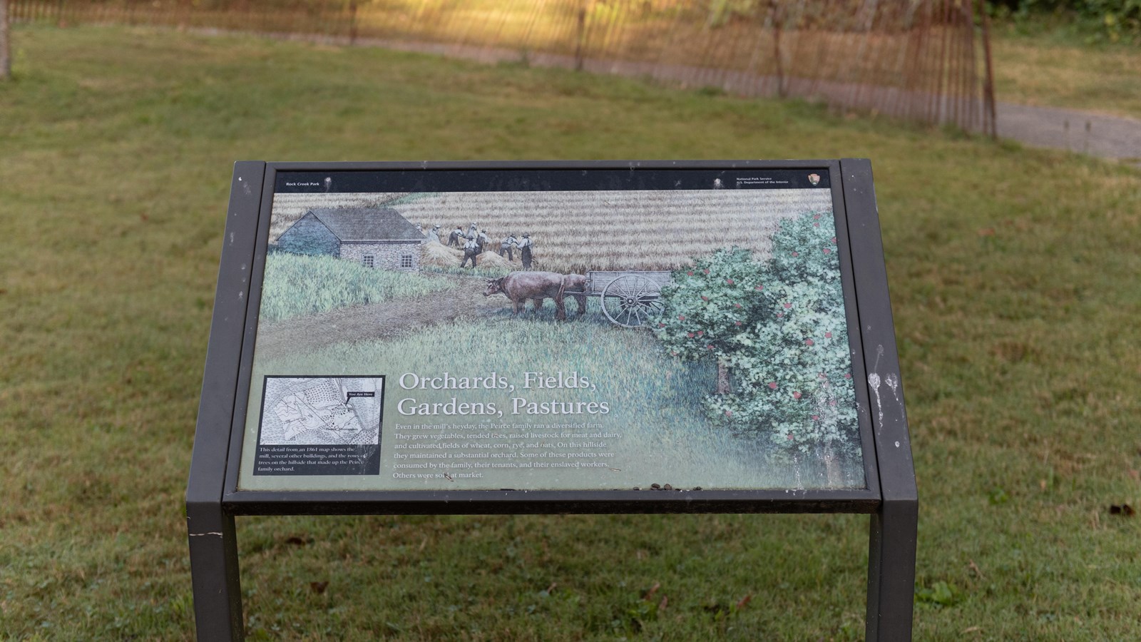 An informational panel in front of a grassy field. 