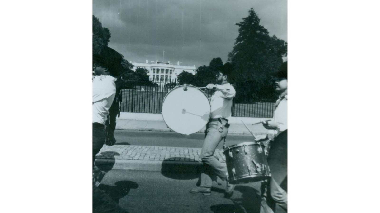 3 men playing different drums marching in front of the South Lawn of the White House