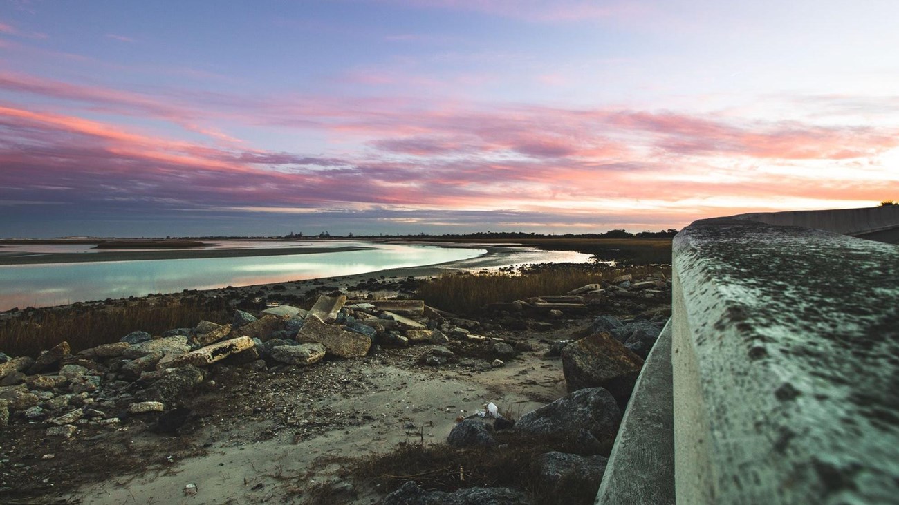 pink and purple sunrise next to seawall and river