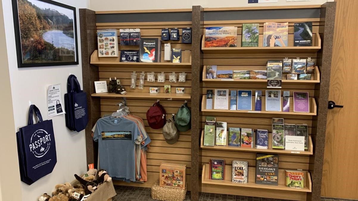 A 10 foot section of wall with shelves of books and souvenirs for sale.