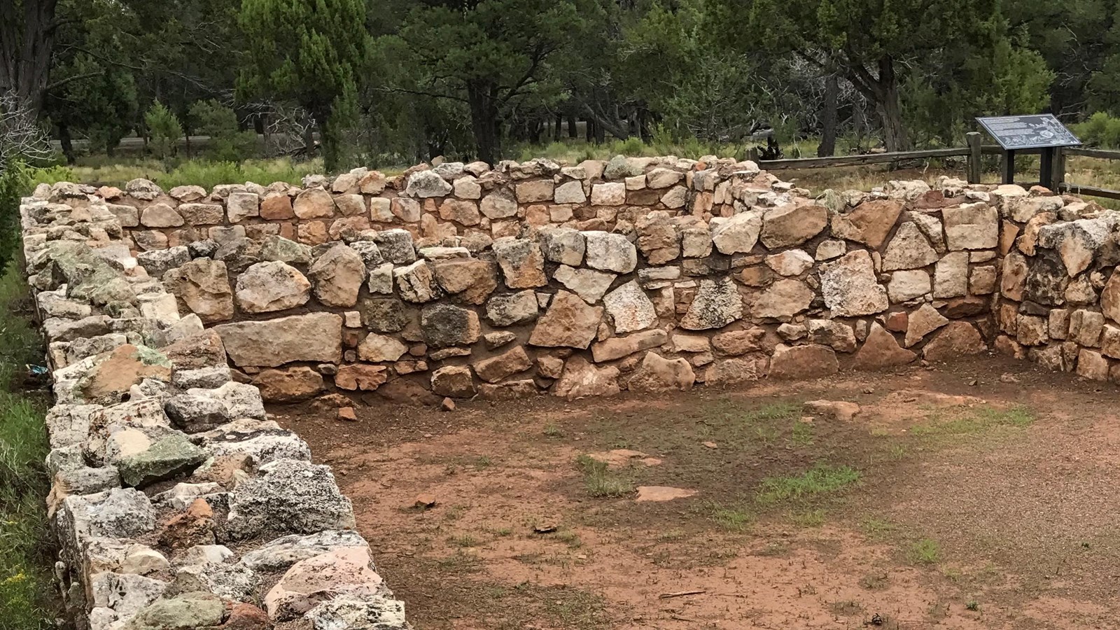  short limestone wall outlines two rooms of a partially reconstructed pueblo. 