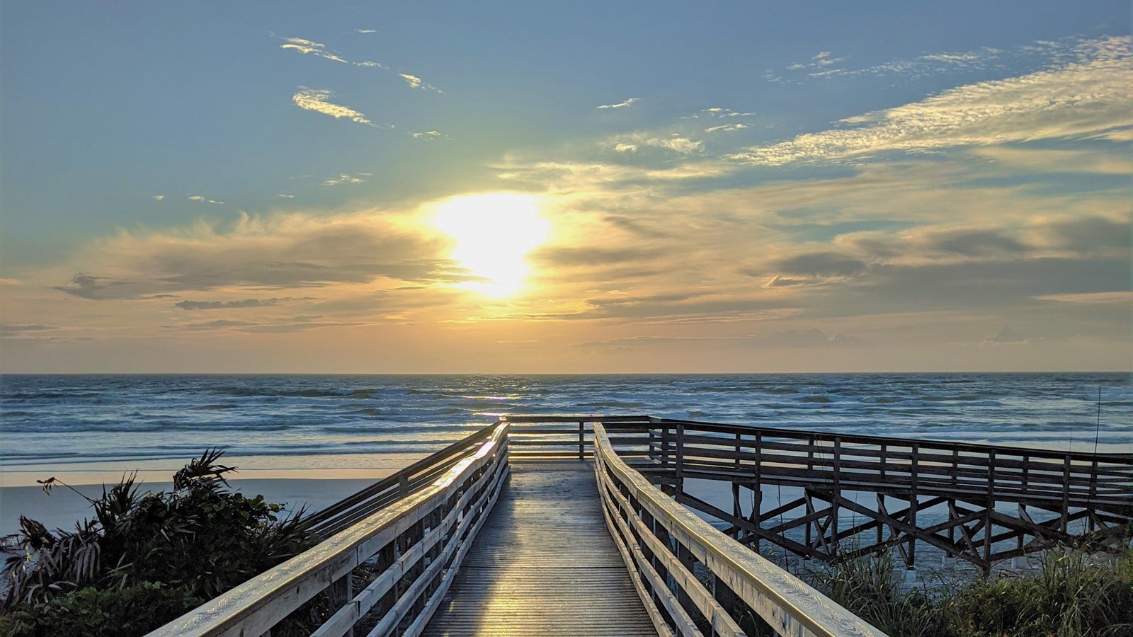 Boardwalk centered with ocean in the background at sunrise