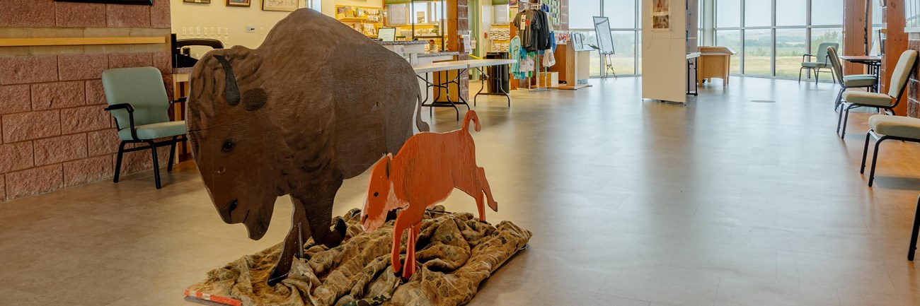 A large gallery with a high cathedral style ceiling, red stone walls, and wooden bison.
