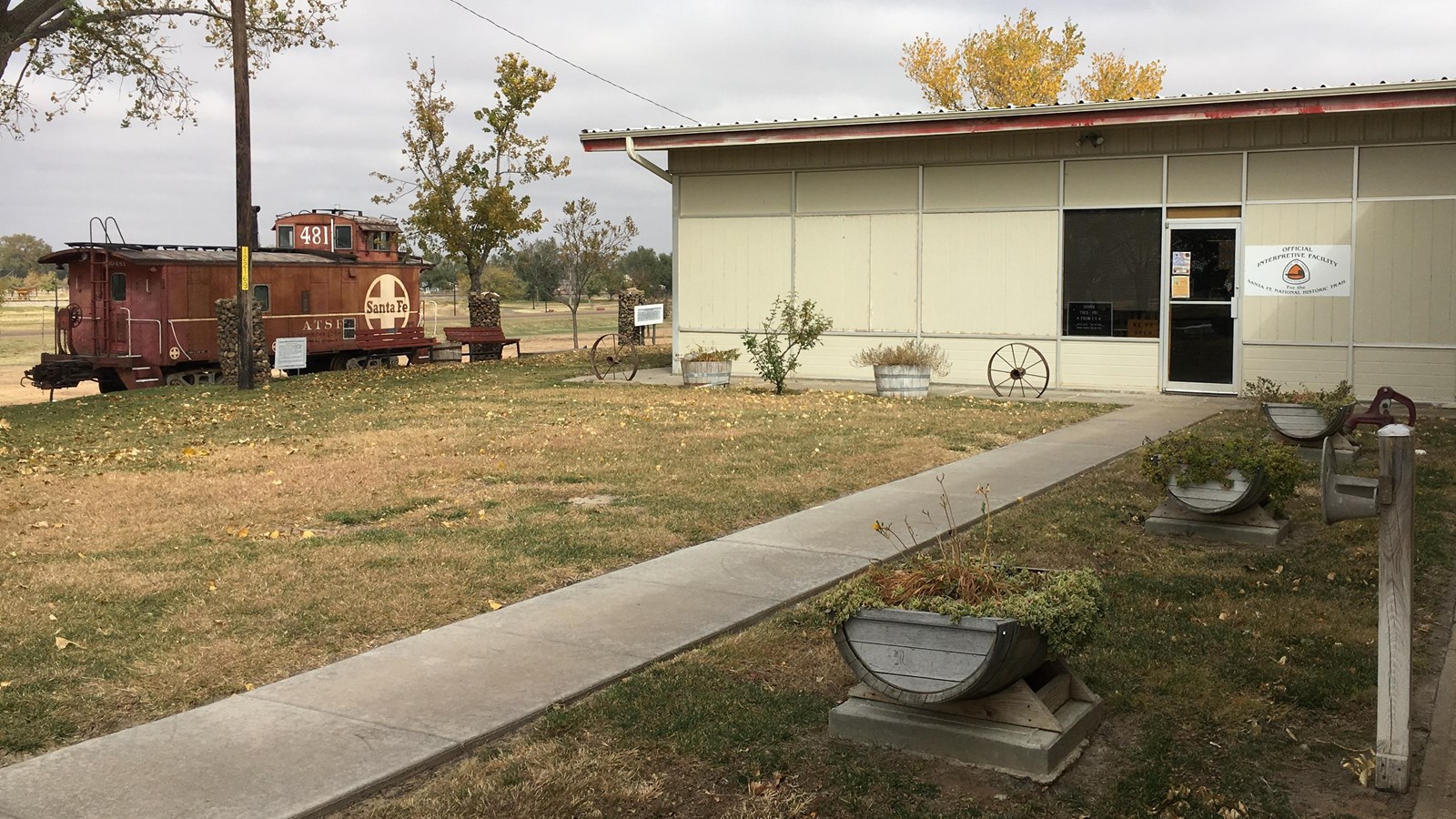 A cement path leads to a one story museum building entrance door.