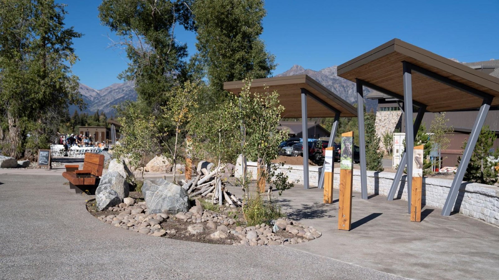 An open plaza with a bench, awnings, plants, and exhibits.