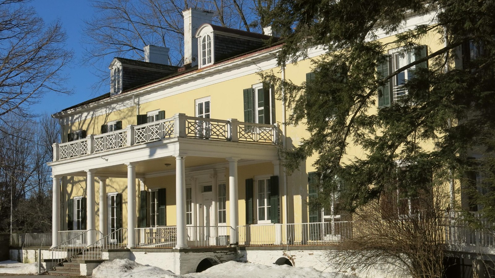 A yellow house with central raised portico.