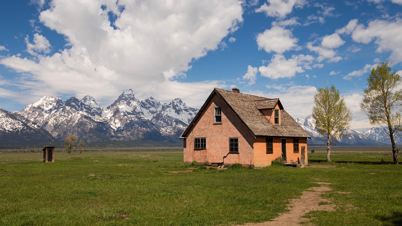 A salmon colored house with mountains in the background.