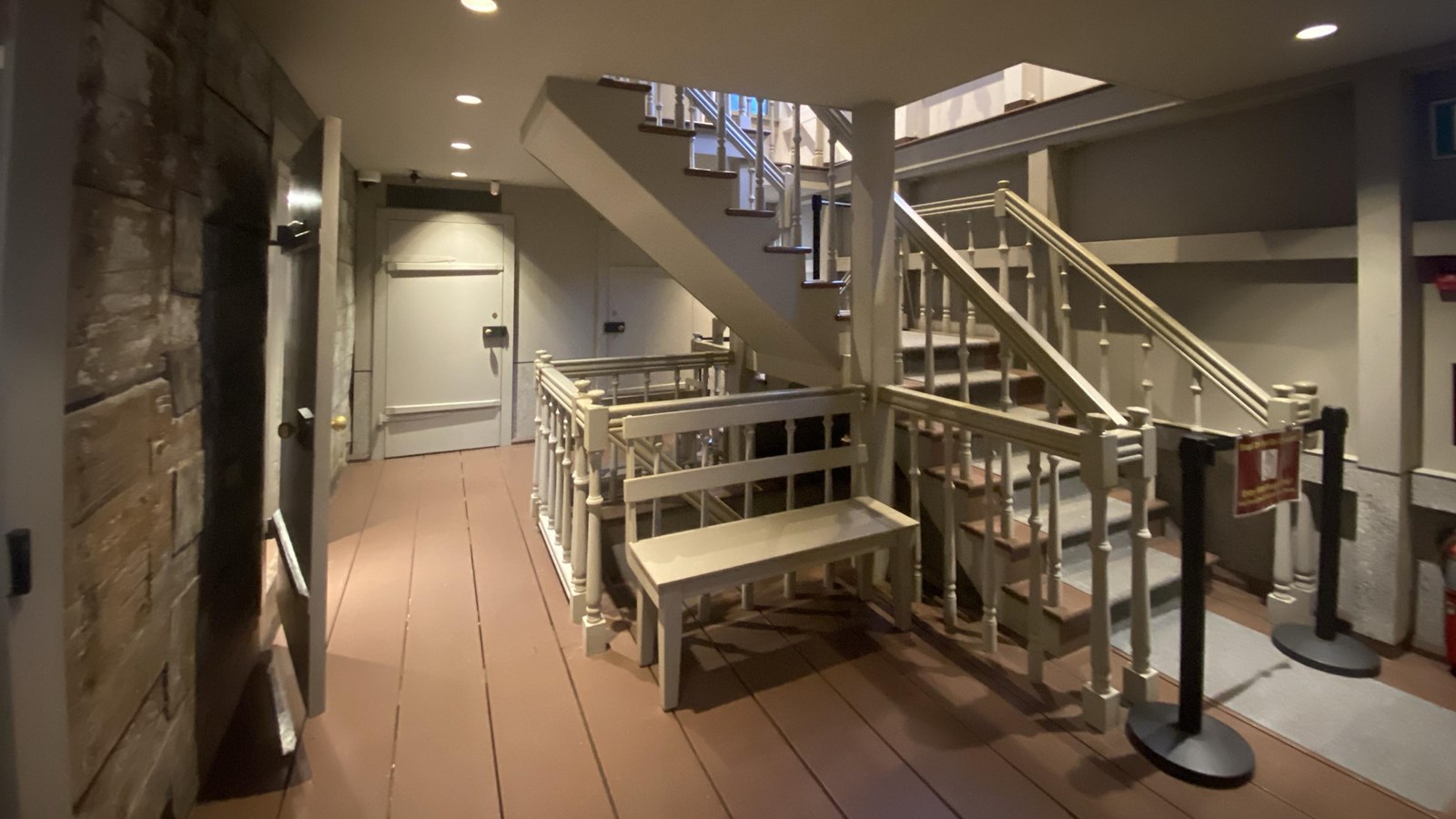 open stairwell that goes up with a gated one underneath that goes down walls painted grey red floors