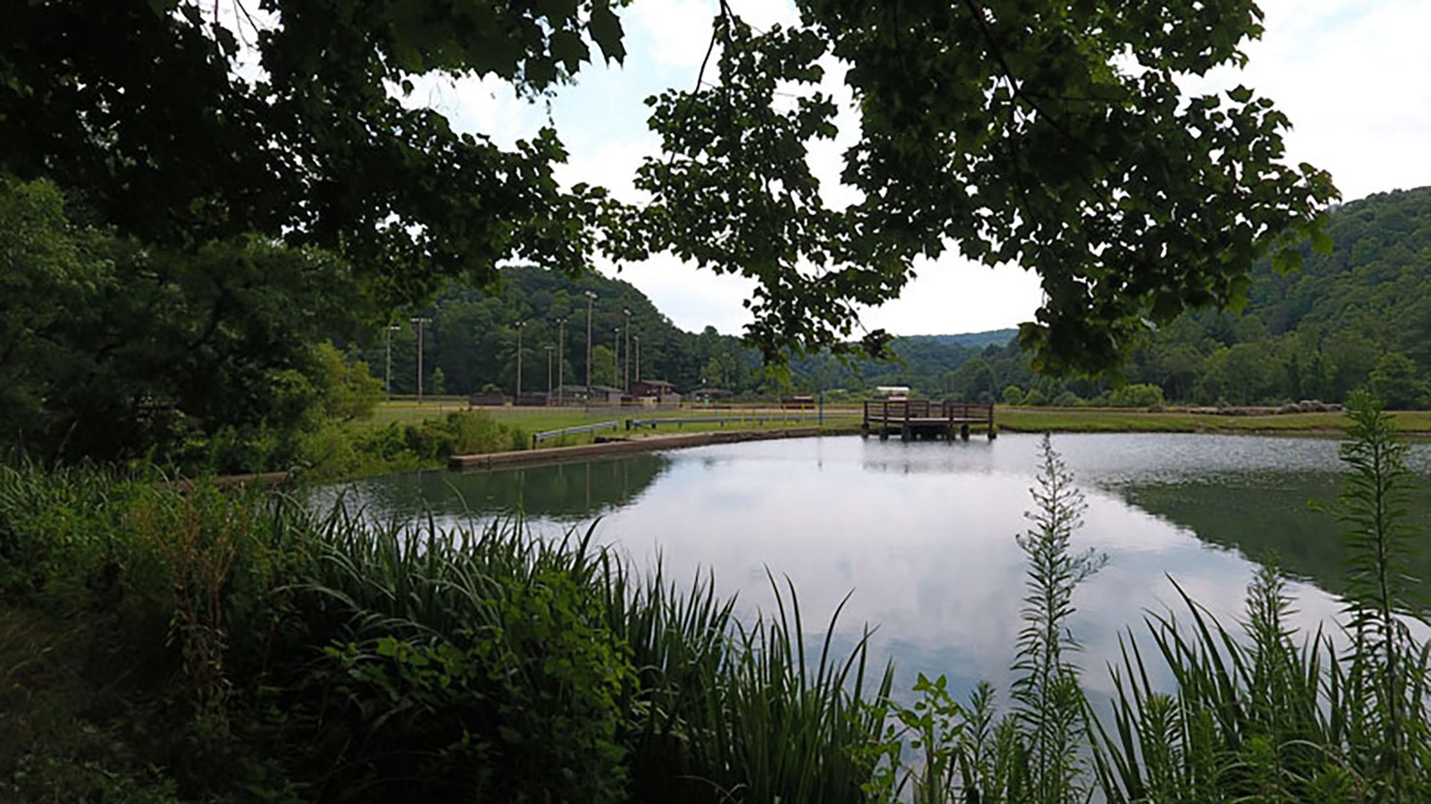 pond with dock and small wood buildings on opposite side