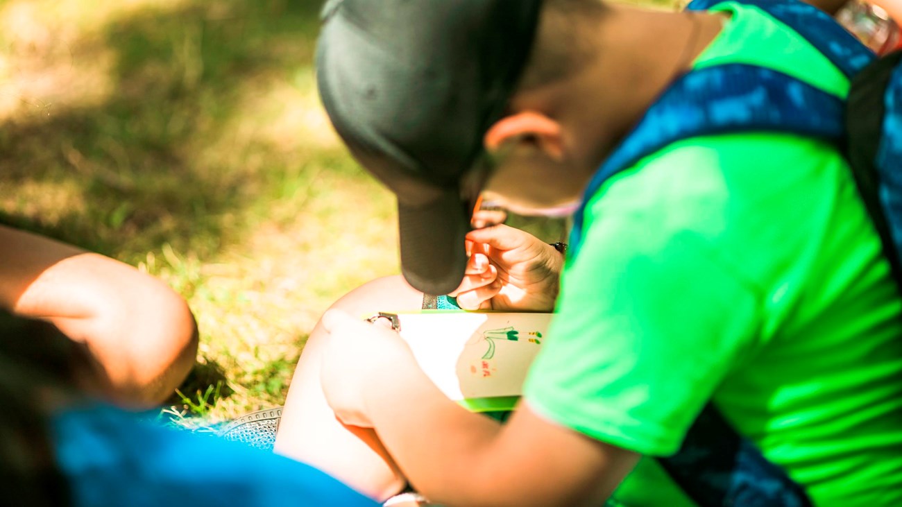 A kid sitting on the ground looking down at an activity he is working on. 